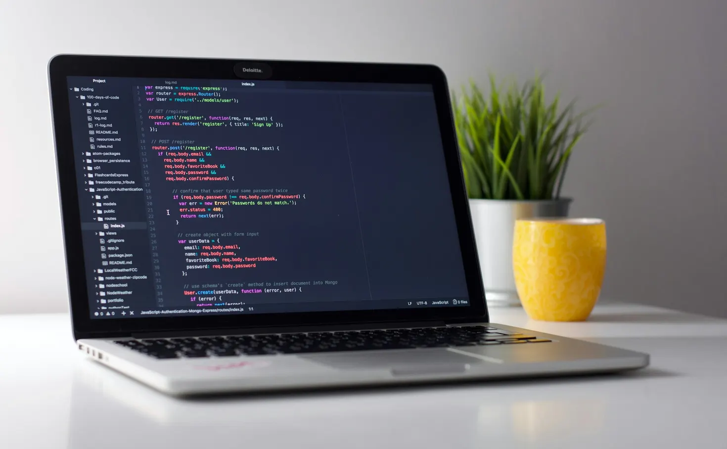 Laptop on a white desk showing code in an editor